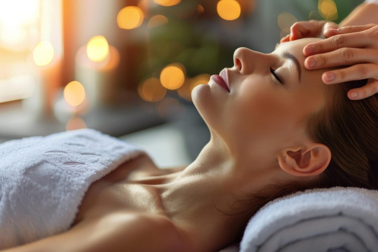 Femme détendue sur une table de massage qui se fait masser le visage miracle face bien-être